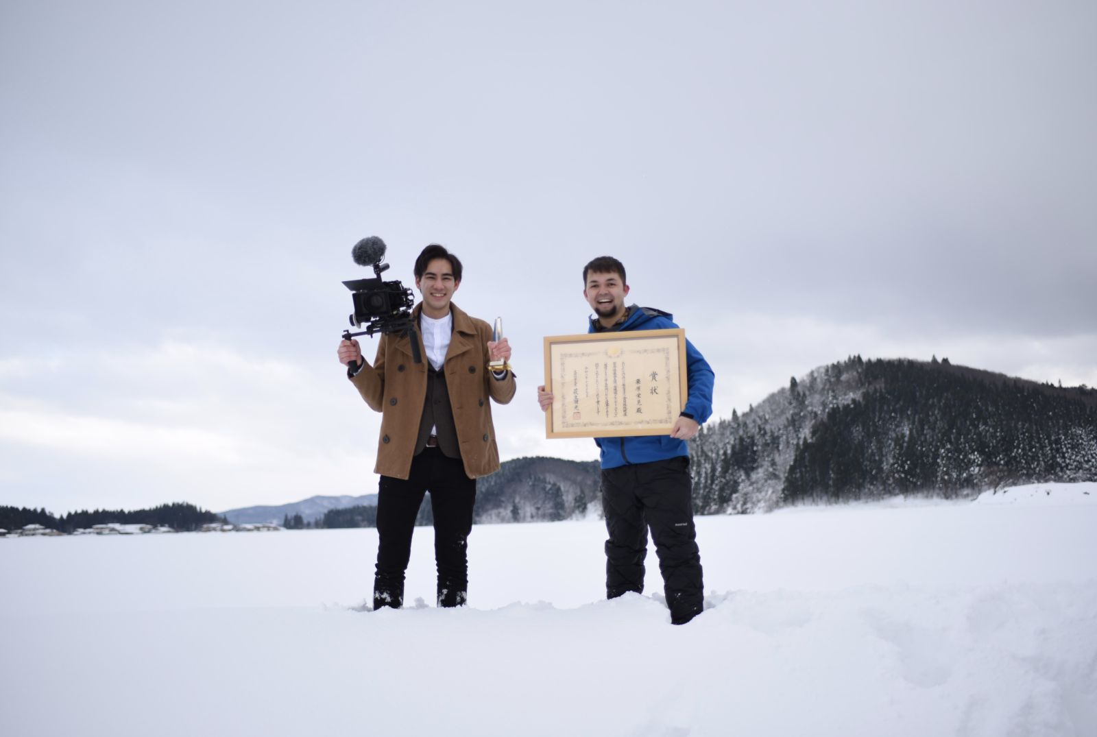 雪の中トロフィーを持つ２人